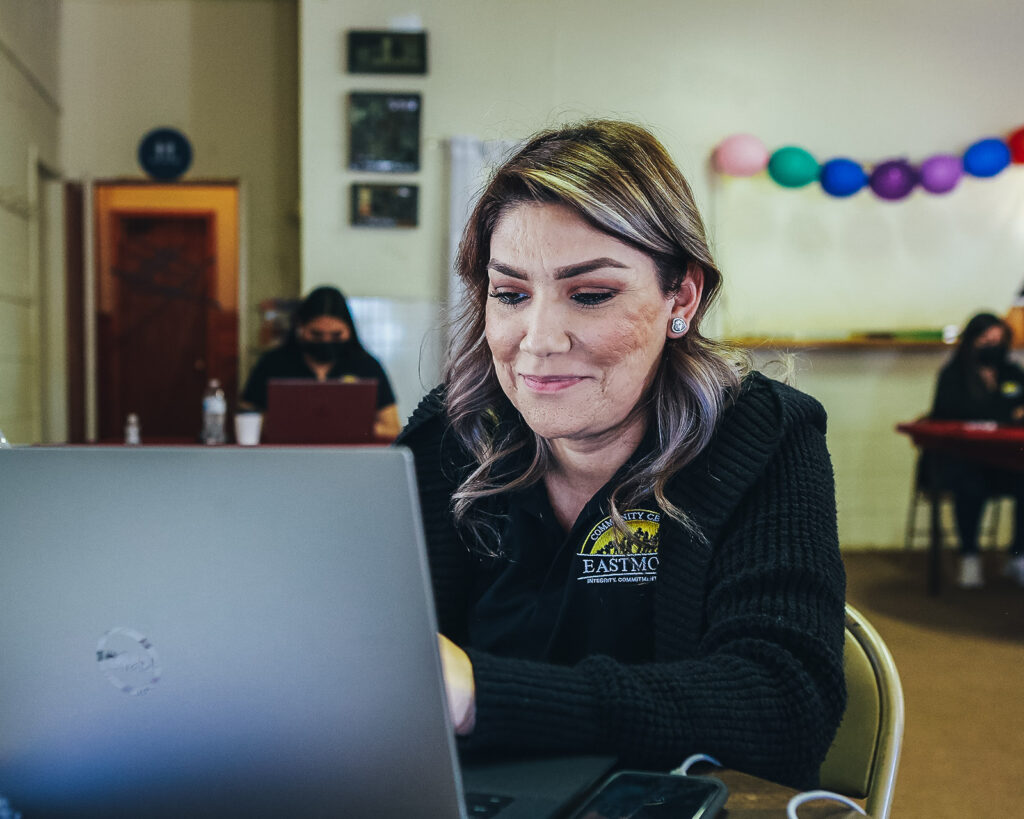 Smiling woman sits in front of a computer.