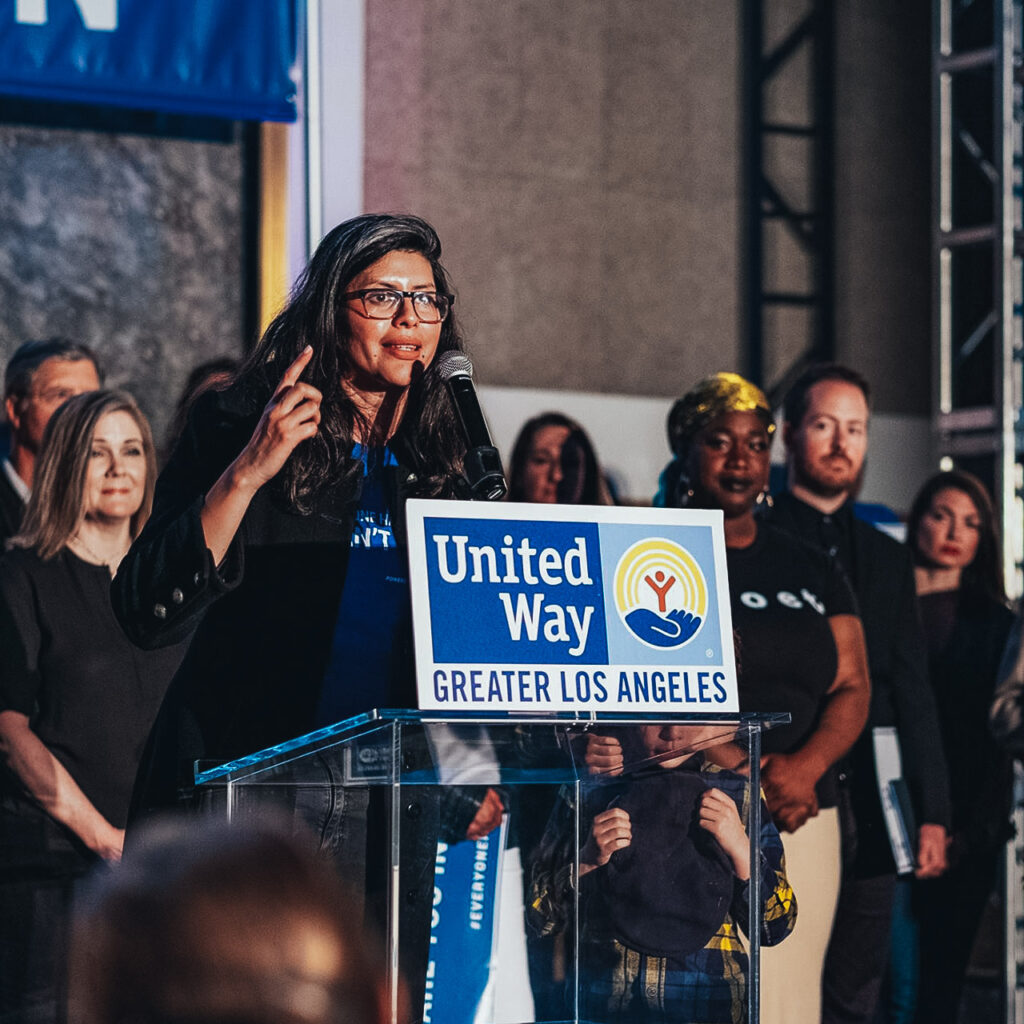 Woman at podium with United Way logo calls a surrounding crowd to action