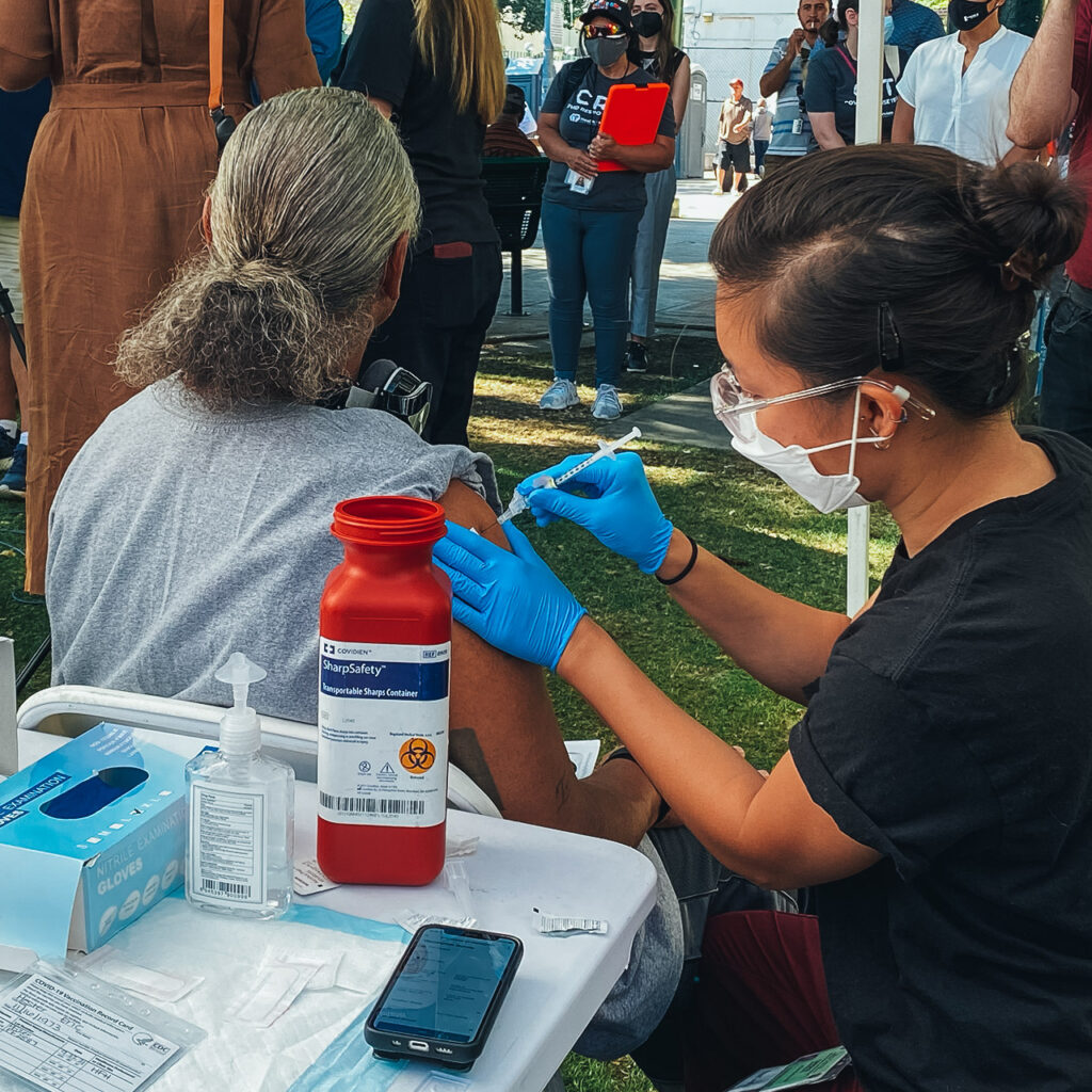 Medical outreach worker adminsiters a vaccine to to a patient