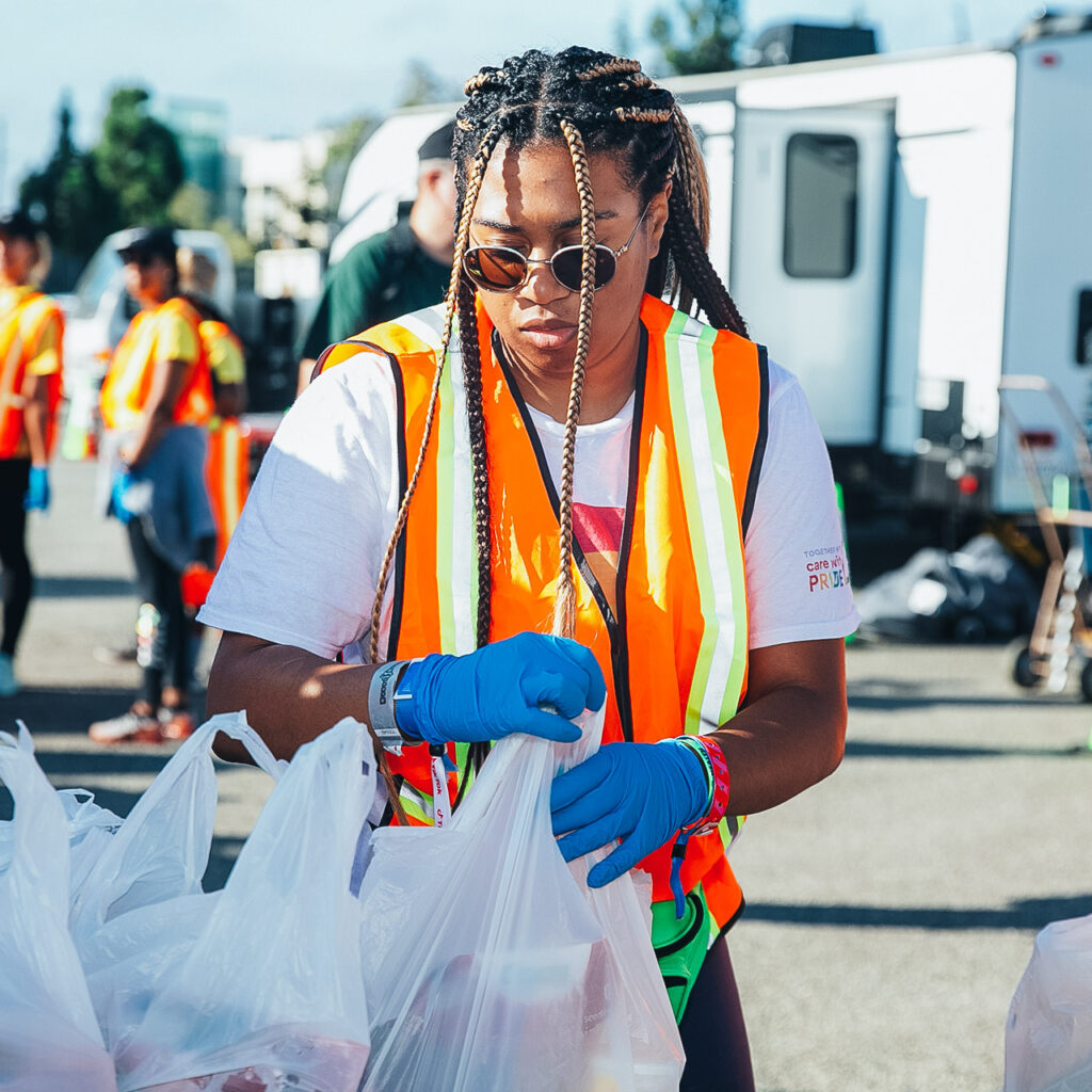 A volunteer in a bright orange vest helps assemble packages at a food drive