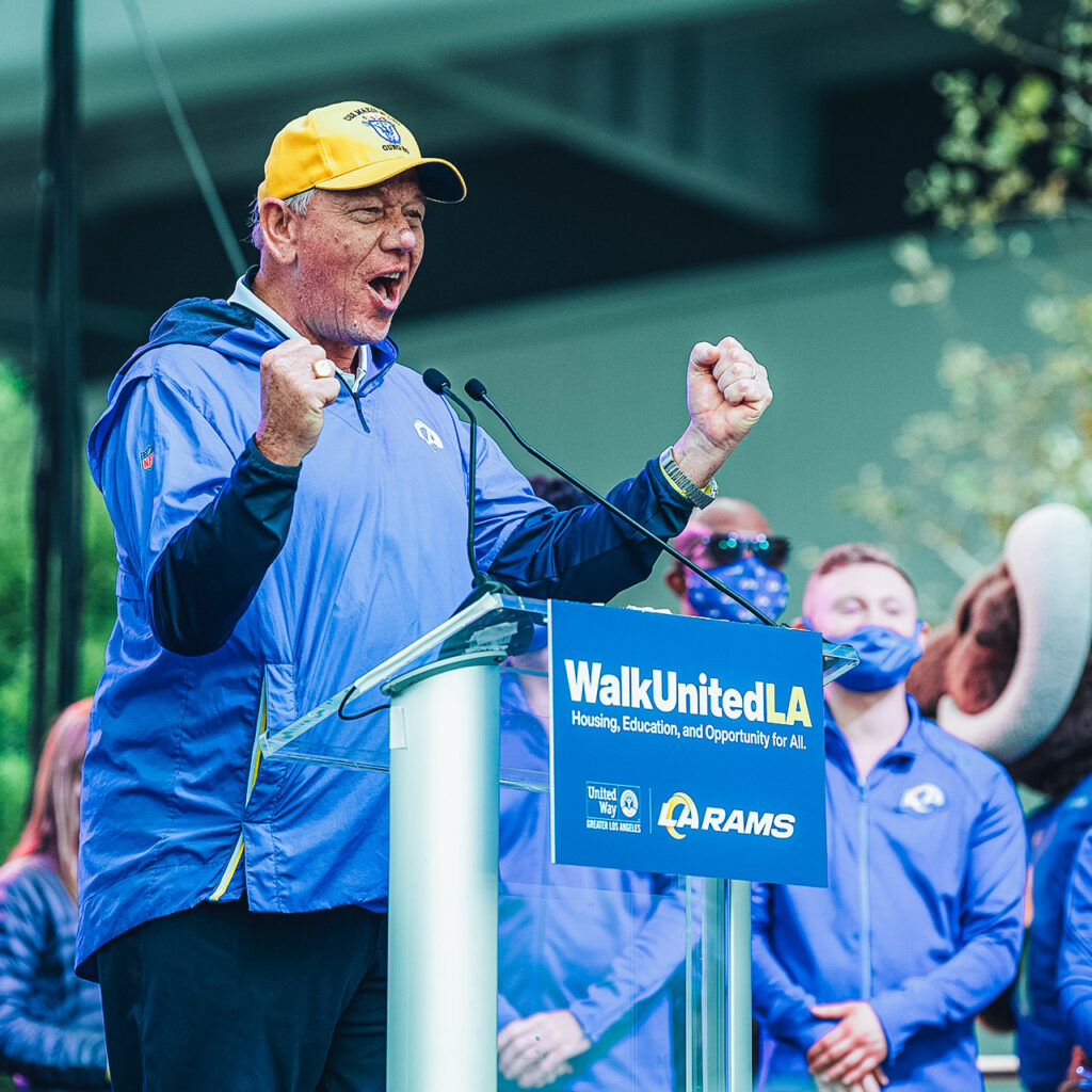 A representative from the LA Rams speaks at a Walk United event, clenching fists and joyously engaging his audience