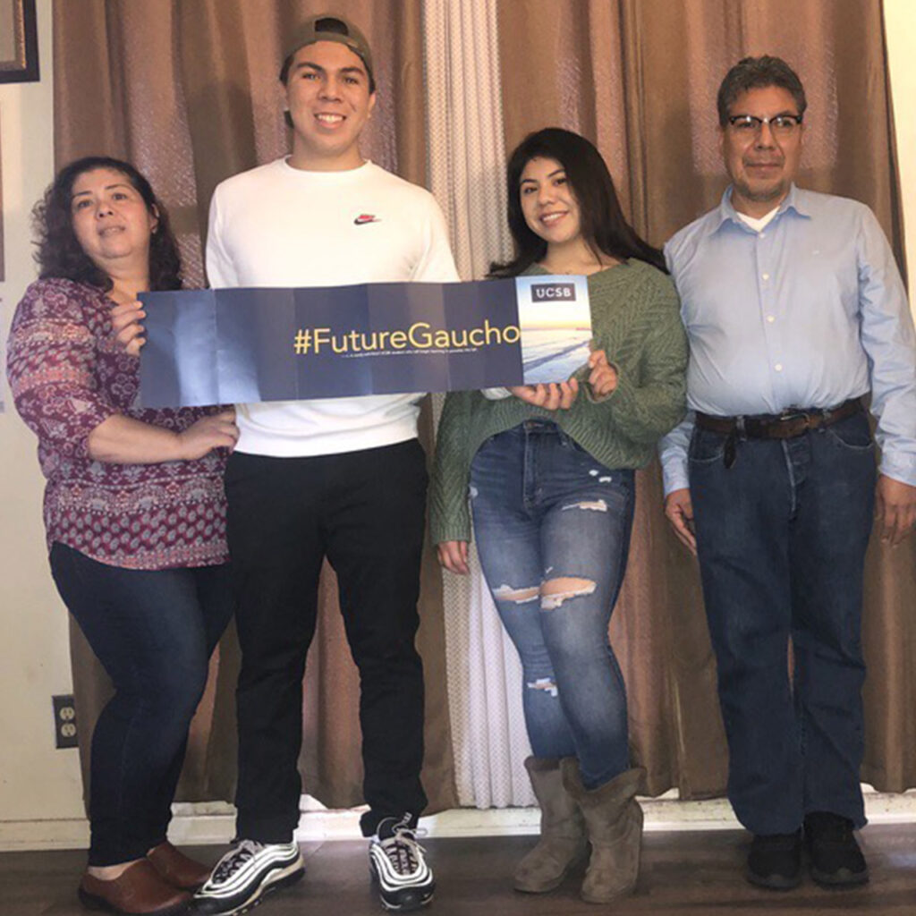 Oscar posing with three family members holding a sign that reads #FutureGauchos