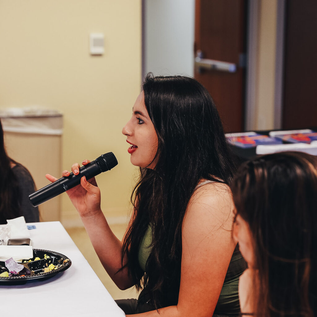 Yecenia speaking into a microphone at a Youth Civic Leadership Program event